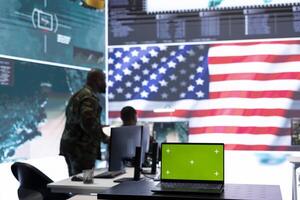 American army working in a command post with green screen, soldiers examining satellite imagery for clues regarding a national safety operation. US military control tower for surveillance. photo
