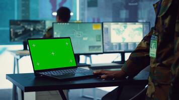 Commander examines a greenscreen on laptop in military command center, reconnaissance army division. Operator gathering intelligence from the field, transmitting real time data. Camera A. photo