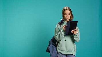 Woman scrolling on tablet touchscreen, checking social media feed, catching up with friends. Happy person relaxing by browsing internet websites, isolated over studio background, camera B photo