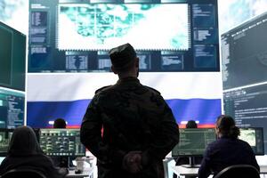Military expert hacker from Russian army working in governmental operations center, breaking into rival states network to spread fake news and hybrid war propaganda. Brainwashing strategy. photo