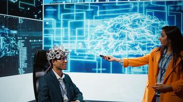 Presenter talking at AI neuroscience forum bringing together IT professionals, showing EEH headset demonstration of latest developments in artificial intelligence mind transfer, camera B photo
