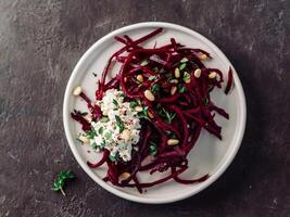 Raw beetroot spaghetti salad with soft cheese,nuts,thyme.Vegetable noodles - Fresh Beetroot Noodles with Ricotta and fresh thyme on plate. Copy space.Clean eating, raw vegetarian food concept.Top view photo