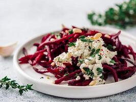 Raw beetroot spaghetti salad with soft cheese, nuts, thyme. Vegetable noodles - Fresh Beetroot Noodles with Ricotta and fresh thyme on plate. Copy space. Clean eating, raw vegetarian food concept photo