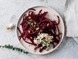 Raw beetroot spaghetti salad with soft cheese,nuts,thyme.Vegetable noodles - Fresh Beetroot Noodles with Ricotta and fresh thyme on plate. Copy space.Clean eating, raw vegetarian food concept.Top view photo