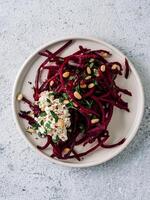 Raw beetroot spaghetti salad with soft cheese,nuts,thyme.Vegetable noodles - Fresh Beetroot Noodles with Ricotta and fresh thyme on plate. Copy space.Clean eating, raw vegetarian food concept.Top view photo