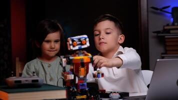 Two kids playing with robot from building blocks at home photo