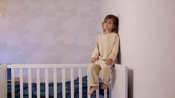 a little girl four years old sits in a bright room in a crib and smiles photo