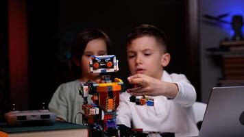 Two kids programming robot from building blocks at home photo