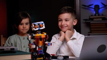 Two kids programming a robot from a laptop at home photo