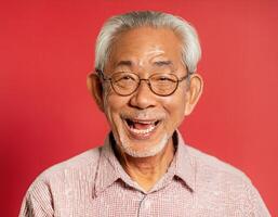 A men with 85 years old looking at the camera with excited facial expression in front of the red background photo