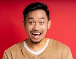 A men with 35 years old looking at the camera with excited facial expression in front of the red background photo