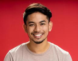 A men with 25 years old looking at the camera with excited facial expression in front of the red background photo