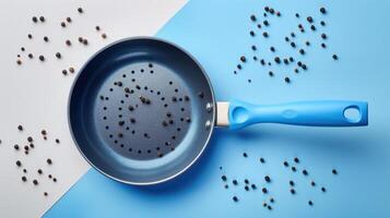 Non-Stick Frying Pan with Blue Handle and Scattered Peppercorns on a Blue and White Background photo
