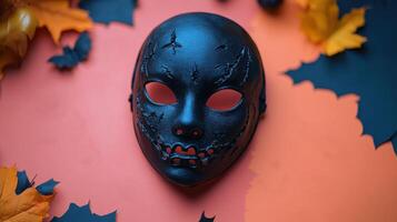 Black Halloween Mask with Bat and Leaf Decorations on Orange Background photo