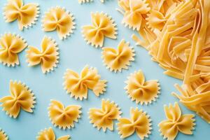 Assorted Uncooked Pasta on Light Blue Background - Farfalle and Fettuccine Arranged in a Pattern photo