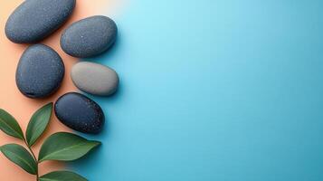 Zen-Inspired Minimalist Background with Smooth Stones and Green Leaves on Dual-Tone Surface photo