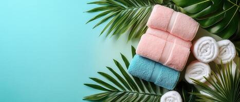 Colorful Towels and Rolled White Towels on Tropical Leaves with Light Blue Background photo