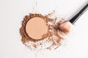 A sample of a round block of compact powder in a brown tone and a chic brush for applying makeup. loose powder sample. top view. layout for design photo