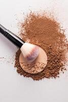 A sample of a round block of compact powder in a brown tone and a chic brush for applying makeup. loose powder sample. top view. layout for design. photo