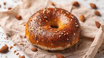 Freshly Baked Bagel with Poppy and Sesame Seeds on Parchment Paper Surrounded by Almonds photo