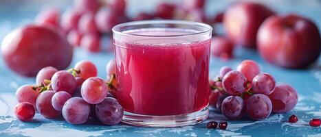 Fresh Grape Juice in a Glass Surrounded by Red Grapes and Plums on a Blue Rustic Table photo