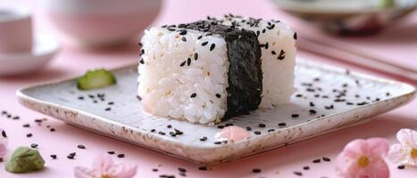 Delicious Japanese Onigiri Rice Ball with Seaweed and Sesame Seeds on Ceramic Plate with Pink Background photo