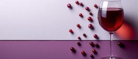 Elegant Wine Glass with Red Wine and Scattered Grapes on a Modern Purple and White Background photo