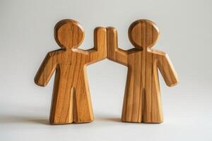 Wooden Figures High-Fiving Symbolizing Teamwork, Unity, and Friendship on a Neutral Background photo