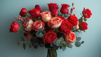 Elegant Bouquet of Red and Pink Roses with Eucalyptus Leaves Against a Soft Blue Background photo