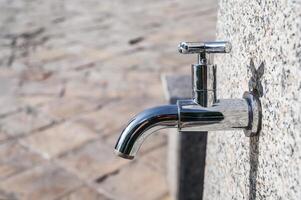 modern metal outdoor faucet with clean drinking water in park on street in the city in summer close-up photo