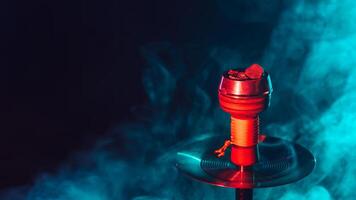 hot red coals for hookah shisha in a metal bowl with smoke on a color background with a copy space photo