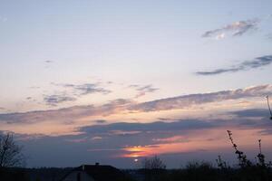 sunset spring sky over the roof of a house photo