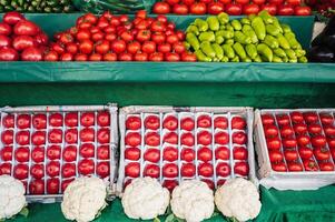 counter with fresh vegetables at grocery farmers market. Tomatoes, cucumbers, cauliflower and peppers on store shelves photo