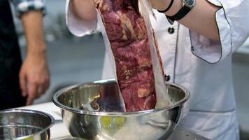 Beef tenderloin. Raw beef steak cut Chef sharpening his knife in front of kitchen table. Cooker preparing his tools before cutting raw pieceof meat and various vegetables 4k footage video