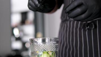 Add lemon to glass. Making lemonade, summer drink, cold drink, healthy liquid. Throw a slice of lemon into a glass Forceps throw lemon water glass closeup. Cold water with fruit slice video