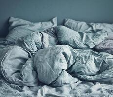 Cozy modern bedroom with rumpled bedding in soft blue tones photo