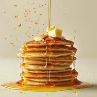 Syrup is being poured onto a stack of pancakes, creating a visually appealing effect. photo