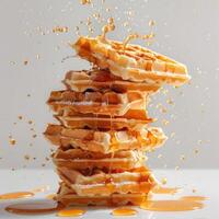Stack of golden waffles falling apart and melting into a pool of syrup, photo