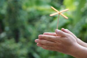 Hands holds DIY fly spinning fan that made from ice cream stick. Concept, Recycle crafts. Toy for kids. teaching aids, educational materials. Creative craft lesson. photo
