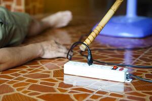 Using wooden stick is moving away the electric plug socket from the unconscious man who lay down on the floor. Concept, Electric Shock. Emergency basic rescue. First Aid photo