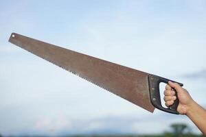 Close up carpenter hand holds old saw. Concept, tool for cutting. Carpentry , woodwork and construction work tool. Carpentry. use for cutting wood. Handsaw for carpenter. photo