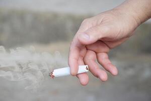 Close up hand holds homemade cigarette for smoking. Concept, smoking is bad for health. Private favorite for relaxation but can cause health problems respiratory disease and addict. photo