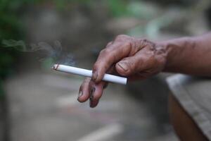 Close up unhealthy hand holds homemade cigarette for smoking. Concept, smoking is bad for health. Private favorite for relaxation but can cause health problems and bad smell. photo