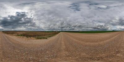 hdri 360 panorama on wet gravel road among fields in spring nasty day with storm clouds in equirectangular full seamless spherical projection, for VR AR virtual reality content photo