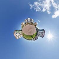 abstract swirling tiny planet spherical panorama of multi-storey buildings of skyscrapers of a residential complex in the form of a butterfly, bugs, crabs in blue sky photo