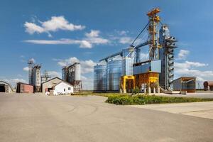 modern granary elevator with silver silos on agro-processing and manufacturing plant for processing drying cleaning and storage of agricultural products, flour, cereals and grain. photo