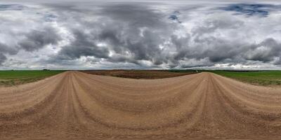 hdri 360 panorama on wet gravel road among fields in spring nasty day with storm clouds in equirectangular full seamless spherical projection, for VR AR virtual reality content photo