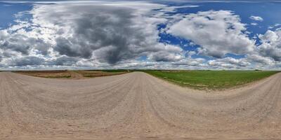 hdri 360 panorama on wet gravel road among fields in spring nasty day with storm clouds in equirectangular full seamless spherical projection, for VR AR virtual reality content photo