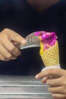 Close up hand of a person scooping ice cream in to a cone with blurred background photo