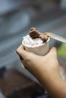Close up hand of a person scooping ice cream in to a paper bowl with blurred background photo